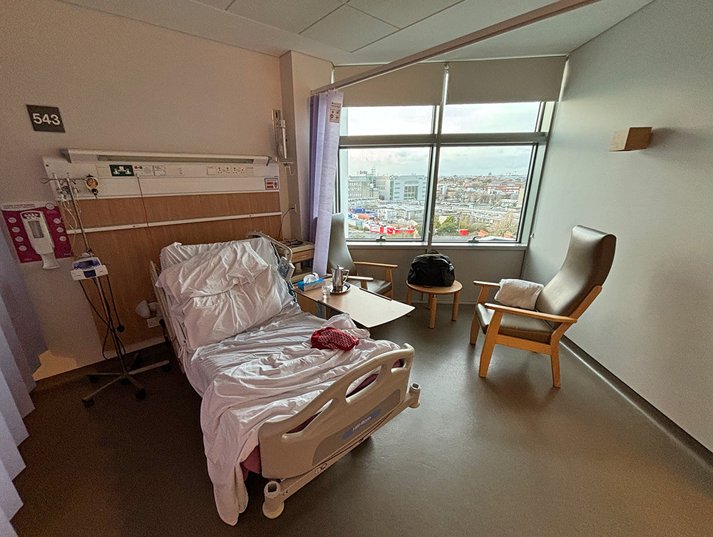 Hospital bed with a large window and seating area